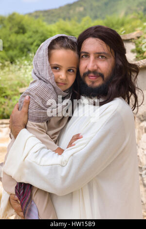 Biblische Szene, in der Jesus sagt: Lasst die Kinder kommen zu mir, ein kleines Mädchen Segen. Historisches Reenactment an einem alten Brunnen. Stockfoto