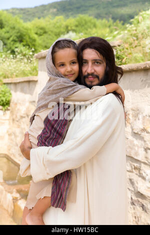 Biblische Szene, in der Jesus sagt: Lasst die Kinder kommen zu mir, ein kleines Mädchen Segen. Historisches Reenactment an einem alten Brunnen. Stockfoto