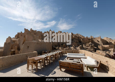 Traditionelle alte arabische Erbe Haus Lodge auf dem Dach mit Wohn / Holztischen und Stühlen mit Blick auf die Altstadt Stadtmauer in Siwa Oase Ägypten Stockfoto