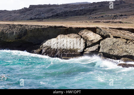 Das azurblaue Wasser des karibischen Meeres Absturzes auf die eingestürzten natürliche Brücke auf der North Shore von Aruba. Stockfoto