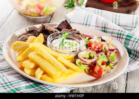 Fleisch vom Grill mit Pommes Frites und frischem Gemüse auf einem Teller Stockfoto