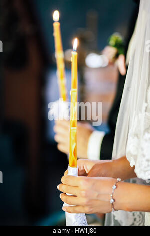 Braut und Bräutigam in der Kirche halten brennende Kerzen Stockfoto