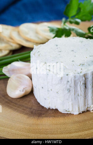 Gewürzte cremige Weichkäse mit Knoblauch und feinen Kräutern auf einer Holzplatte mit Crackern. Stockfoto