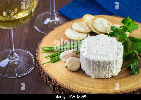 Gewürzte cremige Weichkäse mit Knoblauch und feinen Kräutern auf einer Holzplatte mit Crackern. Stockfoto