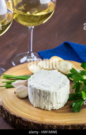 Gewürzte cremige Weichkäse mit Knoblauch und feinen Kräutern auf einer Holzplatte mit Crackern. Stockfoto