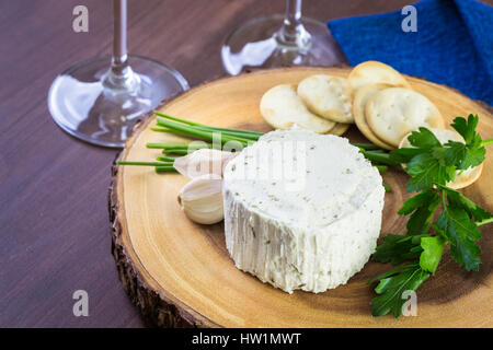 Gewürzte cremige Weichkäse mit Knoblauch und feinen Kräutern auf einer Holzplatte mit Crackern. Stockfoto