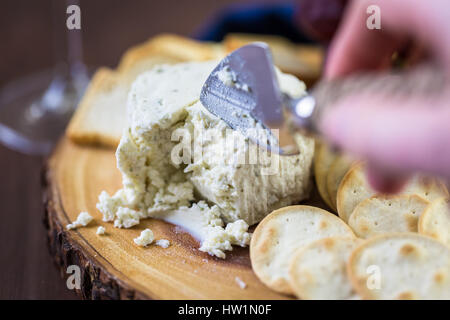 Gewürzte cremige Weichkäse mit Knoblauch und feinen Kräutern auf einer Holzplatte mit Crackern. Stockfoto