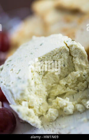 Gewürzte cremige Weichkäse mit Knoblauch und feinen Kräutern auf einer Holzplatte mit Crackern. Stockfoto