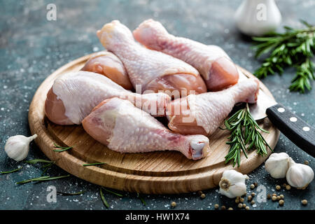 Rohe ungekochte Hähnchenschenkel, Drumsticks auf Holzbrett, Fleisch mit Zutaten zum Kochen Stockfoto