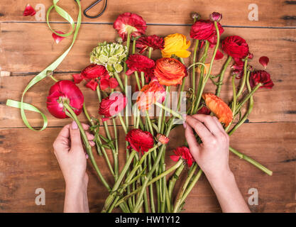 Ranunkulyus Bouquet von roten Blüten auf einem hölzernen Hintergrund Stockfoto