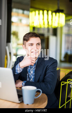 Männlichen Freiberufler verbinden mit WLAN über Laptop-Computer, nachdenklich Geschäftsmann Arbeit auf Net-Book beim Sitzen am Holztisch in modernen Kaffee-sho Stockfoto