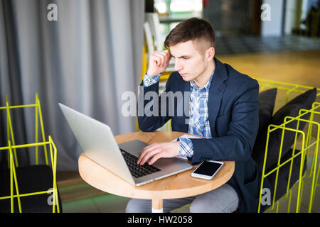 Gespannten junger Mann arbeiten am Laptop an Cafe Tisch Stockfoto