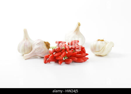 Jede Menge kleine rote Chilischoten und Knoblauch Zwiebeln auf weißem Hintergrund Stockfoto