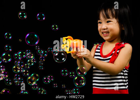 Asiatische chinesische Kinder spielen Seifenblasen innen schwarzer Hintergrund. Stockfoto