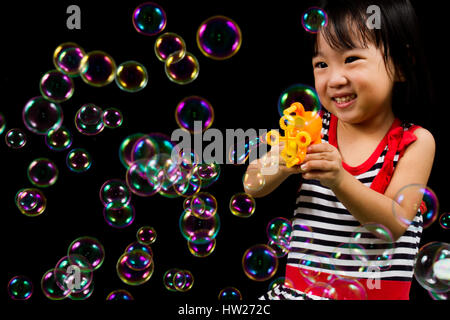 Asiatische chinesische Kinder spielen Seifenblasen innen schwarzer Hintergrund. Stockfoto