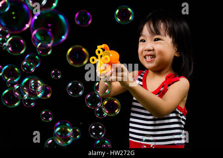 Asiatische chinesische Kinder spielen Seifenblasen innen schwarzer Hintergrund. Stockfoto