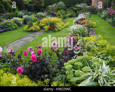 Chenies Manor versunkene Garten Ende Juli mit Rasen, Weg und vibrantly farbigen rosa Dahlien, Nuancen von grünem Laub und Zierteich nach Westen. Stockfoto