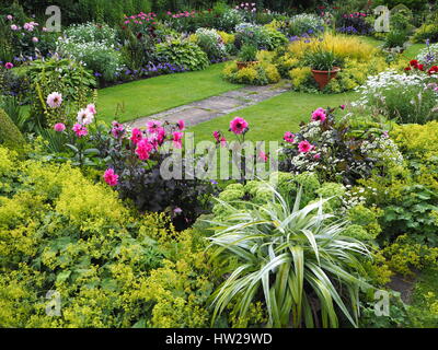 Chenies Manor versunkene Garten Ende Juli mit Rasen, Weg und vibrantly farbigen rosa Dahlien, Nuancen von grünem Laub und Zierteich nach Westen. Stockfoto