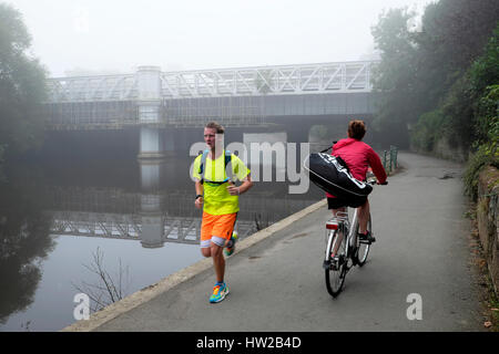 Jogger und Radfahrer auf dem Fahrrad von einem Fluss Severn Railway Bridge auf dem Leinpfad an einem nebligen Morgen im Herbst Shrewsbury, Shropshire, Großbritannien KATHY DEWITT Stockfoto