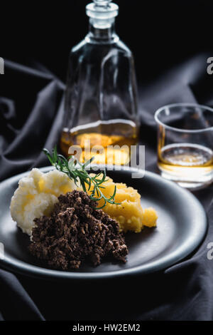 Haggis mit gestampften Rübe, Kartoffeln und Whisky. Stockfoto