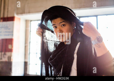 Androgyne asiatischer Mann halten Schal auf Kopf Stockfoto