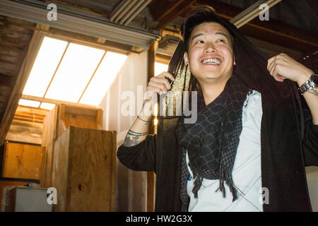 Androgyne asiatischer Mann halten Schal auf Kopf Stockfoto