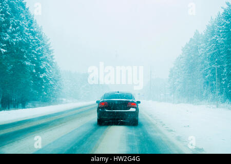 Auto fahren auf Bäumen gesäumten Straße im winter Stockfoto