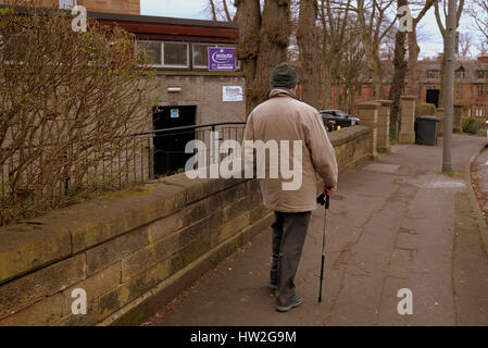 Alter Mann mit Stock zu Fuß auf Straße Pavemebt in Richtung Pfadfinder Hall Tag Zentrum Zeichen Stockfoto