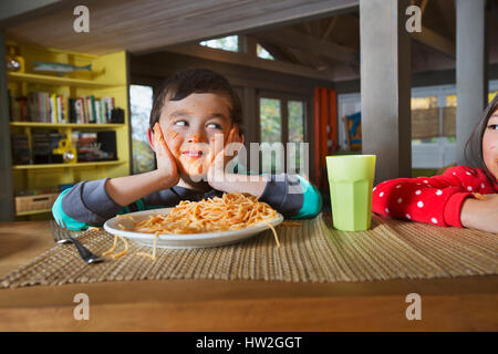 Schwester beobachten Mischlinge Bruder mit chaotisch Gesicht Spaghetti-Essen Stockfoto