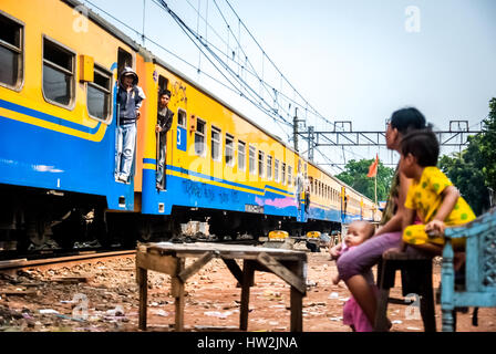 Eine Frau und ihre Kinder beobachten einen Zug, der durch ein Slum in Jakarta, Indonesien, fährt. Stockfoto