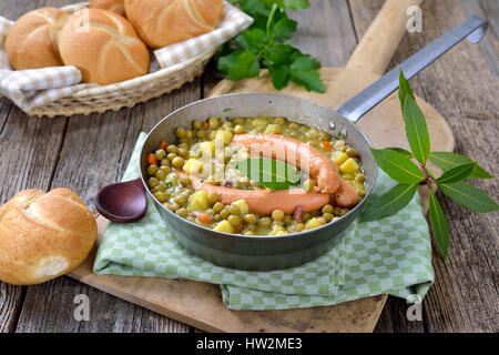 Herzhafte Erbsen-Eintopf mit Kartoffeln, Speck und Wiener Würstchen Stockfoto