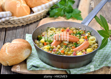 Herzhafte Erbsen-Eintopf mit Kartoffeln, Speck und Wiener Würstchen Stockfoto