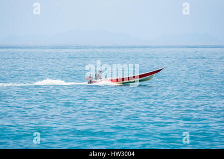 Einziger Mann in ein Speed-Boot mit Außenbordmotor reisen schnell in einem klaren ruhigen blauen Meer. Stockfoto