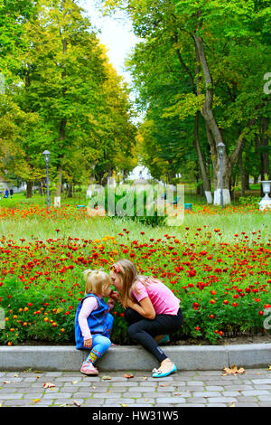 junge glückliche Schwestern riechen mit Bewunderung Wow Ringelblumen im herbstlichen park Stockfoto