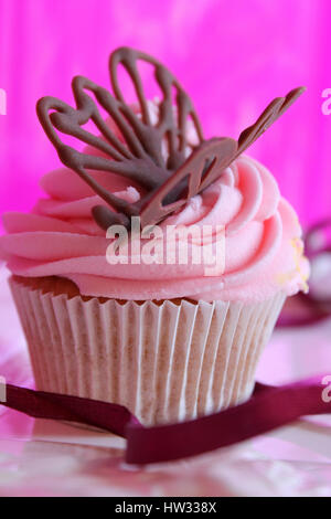 Eine frische, Bio Erdbeer Glasur, Vanille Cupcake in weichem rosa mit einem Hauch von Purpur und eine köstliche Chocolatebutterfly Dekoration auf das Sahnehäubchen gemacht Stockfoto