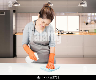 asiatische Haushälterin Reinigung auf Tisch mit Küche-Hintergrund Stockfoto
