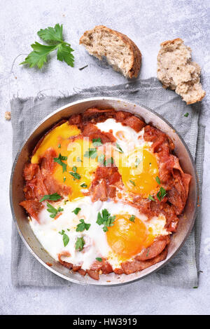 Spiegeleier mit Speck in Pfanne in hellem Stein Hintergrund, Ansicht von oben Stockfoto