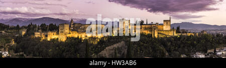 Panorama der lichtstärkeren Alhambra-Palast in Granada, Spanien in der Dämmerung mit Sierra Nevada verschneiten Gipfel. Stockfoto