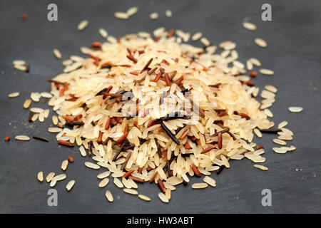 lange Korn Basmati Reis gemischt rot und wild, kleine Haufen auf schwarze Schieferoberfläche Stockfoto