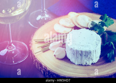 Gewürzte cremige Weichkäse mit Knoblauch und feinen Kräutern auf einer Holzplatte mit Crackern. Stockfoto