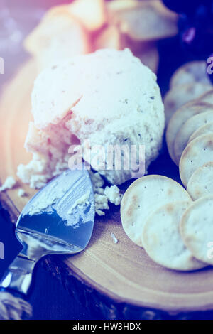 Gewürzte cremige Weichkäse mit Knoblauch und feinen Kräutern auf einer Holzplatte mit Crackern. Stockfoto