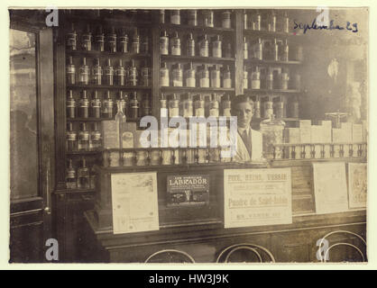 Antikes Foto des Innenraums der Apotheke Shop anzeigen Gläser von Drogen und Medikamenten, Mann - Eigentümer, Mitarbeiter oder Assistenten, Dosieren, in Frankreich datiert September 1929 Stockfoto