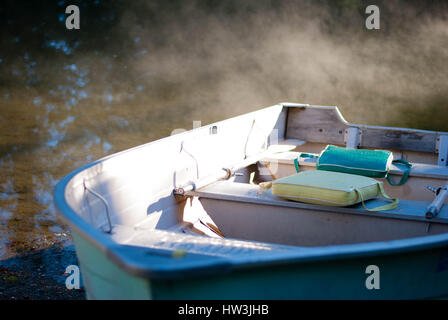 Altes Fischerboot vor Anker auf dem Sand mit der Morgensonne-streaming auf es und Nebel rollt aus dem Wasser. Stockfoto