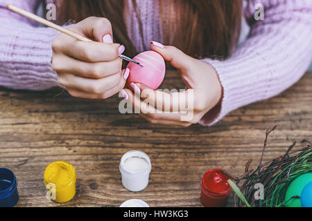 Weibliche Hände bemalen von Ostereiern auf Holztisch. Durchtrainierten Bild. Stockfoto