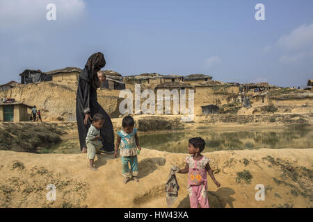 5. März 2017 - findet Cox Bazar, Chittagong, Bangladesch - A Rohingya Frau mit ihren vier Kindern, die vor kurzem aus Myanmar, Bangladesch geflohen Unterschlupf in provisorische Flüchtlingslager, Nahrungsmittelhilfe sammeln.  Etwa 70.000 Rohingya-Muslime flohen nach Bangladesch aus Myanmar seit 9. Oktober 2016 nach dem birmanischen Militär Räumungsarbeiten in Reaktion auf einen Angriff auf die Grenzpolizei ins Leben gerufen. Es gibt mehr als 30.000 registrierte Flüchtlinge in Bangladesch aber Behörden schätzen, dass 300.000 bis 500.000 unregistrierte Rohingya sind auch bereits hier leben. Infolgedessen nicht registriert, die meisten davon Stockfoto