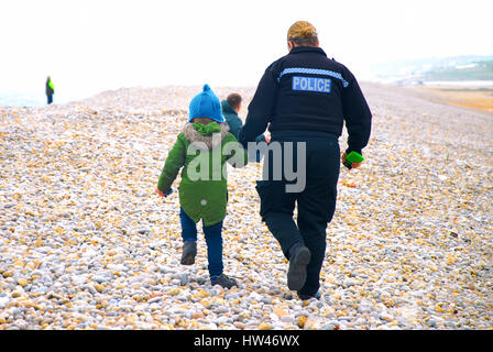 Chesil Beach, Portland, UK. 17. März 2017. Eine Polizistin geht Hand in Hand mit einem kleinen Jungen auf Chesil Beach, Portland, an einem kalten Frühlingstag Credit: Stuart Fretwell/Alamy Live-Nachrichten Stockfoto