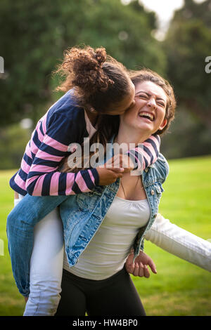 Porträt des Lachens Mädchen tragen Schwester Huckepack Stockfoto