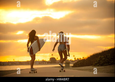 Mädchen im Teenageralter mit Surfbrettern auf skateboards Stockfoto