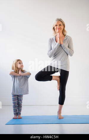 Kaukasische Enkelin beobachten Großmutter Yoga zu praktizieren Stockfoto