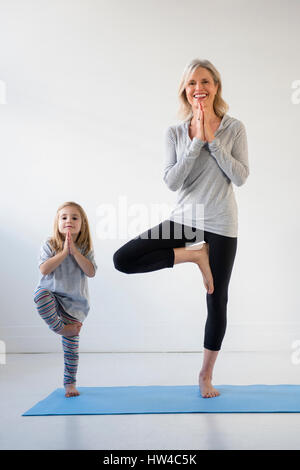 Kaukasische Enkelin imitieren Großmutter Yoga zu praktizieren Stockfoto